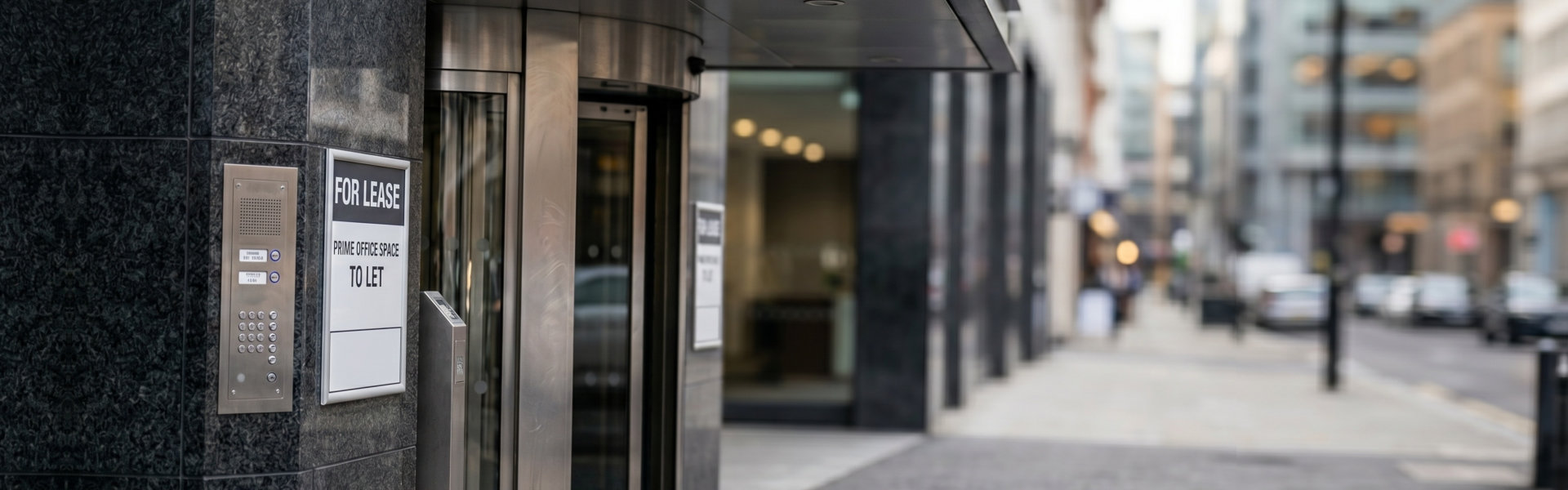 Commercial real estate for lease sign on modern office building entrance with revolving door. Featuring prime city location for business professional headquarters and corporate rental space available.